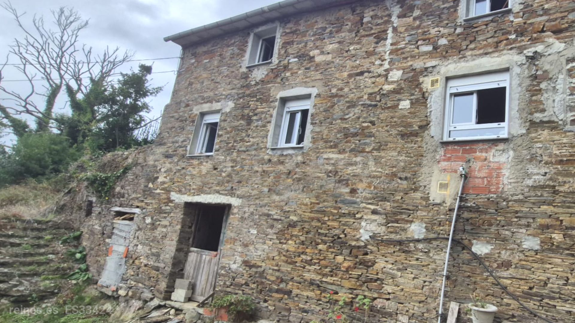 PODEMOS VER LA FACHADA Y JUSTO AL LADO DE LAS ESCALERAS UN TROZO DE TIERRA DONDE ANTIGUAMENTE HABIA UNA CASA AUN SE MANTIENE EL MURO MEDIANERO